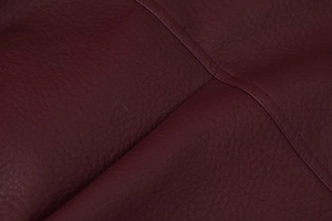 Gros plan sur la texture du cuir bordeaux avec grain fin et double couture de qualité