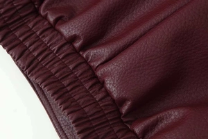 Détail de la veste en cuir bordeaux montrant les poignets élastiques matelassés et le grain