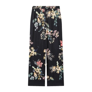 Detailed macro view of floral print wide-leg pants with elegant black hem and elastic waist