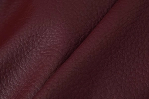 Gros plan sur la texture du cuir rouge foncé avec grain de litchi sur la veste