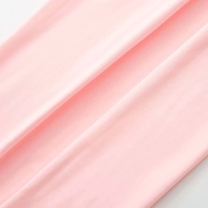 Close-up of soft light pink breathable knitted fabric texture for slim sports jumpsuit