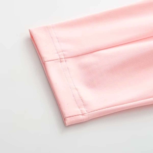 Detail of light pink knit fabric showing precise double-needle stitching and flat seams