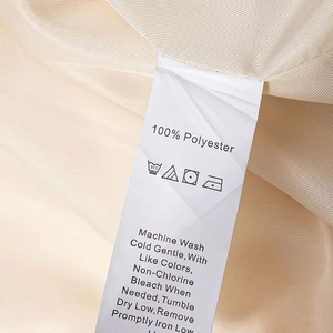 Close-up of the 100% polyester fabric care label on a beige autumn waist-tie coat