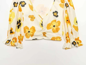 Detail of V-neckline with ruched center and yellow floral print on bubble long sleeves