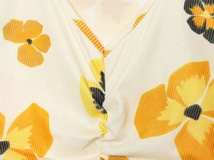 Close-up of V-neckline with pleated detail and yellow floral print on textured fabric