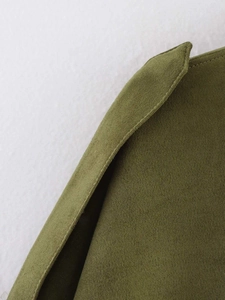 Detail of dark green suede bomber jacket showing premium stitching and fabric texture