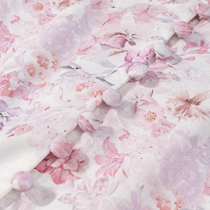 Detailed close-up of pink floral print dress fabric with elegant fabric-covered buttons