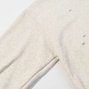 Detail of grey knitted hoodie showing stitching and distressed vintage hole texture
