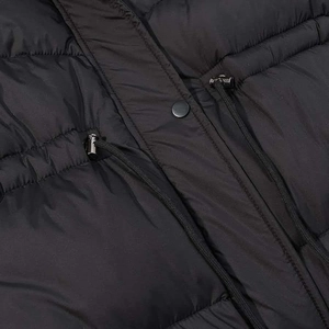 Detail of black quilted winter coat featuring waist drawstring and metal snap buttons