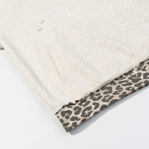Detail of oatmeal hoodie with kangaroo pocket, distressed holes and leopard print hem