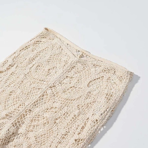 Détail de la maille au crochet beige révélant des motifs floraux et ajourés