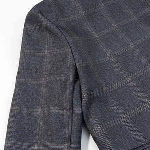 Detailed macro shot of dark grey plaid blazer fabric showing shoulder stitching and texture