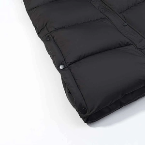 Detail shot of black quilted winter coat featuring metal snap buttons and fine stitching
