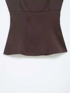 Detail view of dark brown peplum top showing structured seams and textured fabric finish