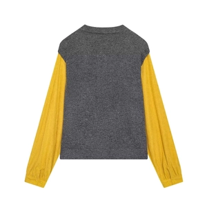 Detail of color-block knit sweater with grey body, yellow sleeves, and buttoned cuffs