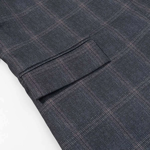 Detailed macro view of grey checkered blazer fabric with precise flap pocket stitching