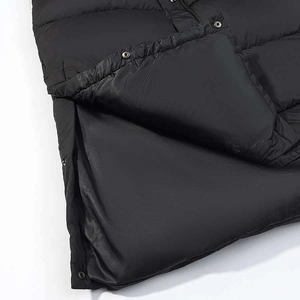 Detailed view of black quilted winter coat featuring silver metal snap buttons and glossy fabric