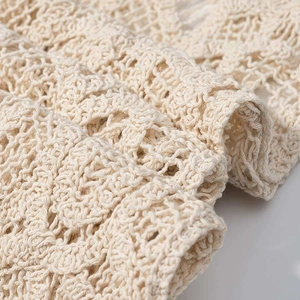 Détail macro montrant la texture complexe du crochet crème et le motif floral ajouré
