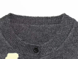 Detail of the crew neck and dark grey knit texture with floral patterns on a sweater