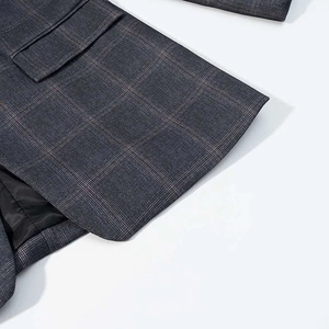 Detailed close-up of dark grey plaid suit fabric texture with pocket and lining