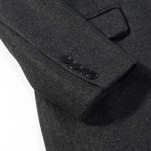 Detailed close-up of four glossy buttons on dark grey wool coat sleeves and fabric texture