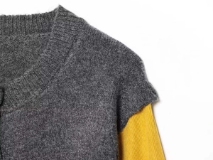 Detail shot of grey wool sweater layered over a yellow ribbed long-sleeve knit top