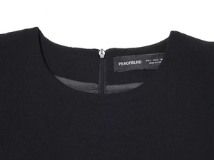 Detail shot of the black crew neck dress featuring a back zipper and woven fabric texture
