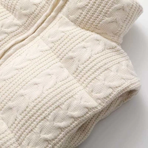 Detailed macro shot of cable knit texture and honeycomb patterns on a beige vest