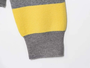 Detail of ribbed cuffs on a grey and yellow striped knit sweater with fine texture