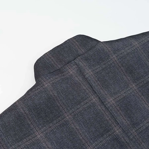 Detailed close-up of dark grey windowpane check wool fabric on a notched lapel blazer