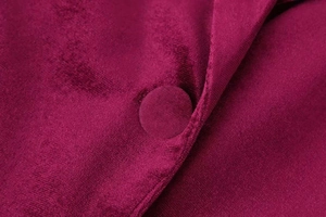 Macro shot of burgundy velvet fabric featuring a matching fabric-covered round button detail