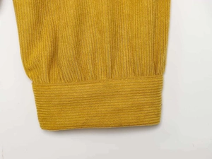 Detailed macro view of yellow corduroy fabric cuffs showing vertical texture and stitching