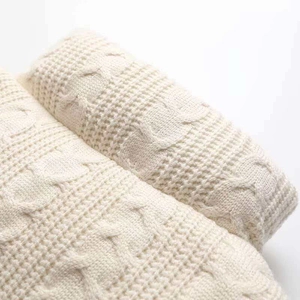 Close-up of thick cable knit texture and waffle weave pattern on cream knitted vest