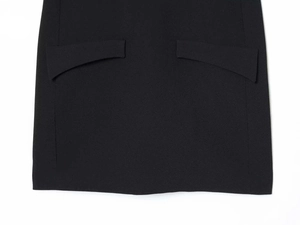 Detailed macro view of symmetric curved flap pockets on the black puff sleeve dress