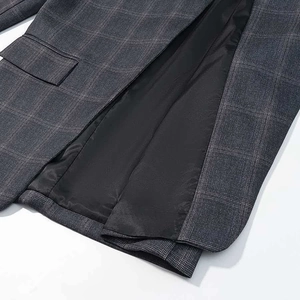 Detail of grey plaid blazer showing fine texture, flap pocket and smooth black lining