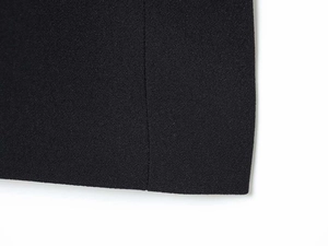 Close-up of black dress fabric showing fine grain texture and vertical seam detail