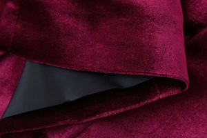 Detailed macro view of burgundy velvet fabric with smooth black lining and fine stitching
