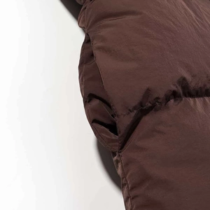 Detailed macro view of dark brown quilted puffer jacket with invisible side pocket