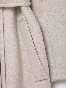 Detail of oatmeal wool coat featuring woven texture, matching belt and side pocket