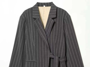 Detail of grey pinstripe blazer featuring a notched lapel and soft beige inner lining