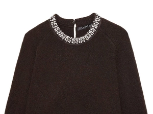 Detail of dark brown knit cardigan featuring rhinestone collar and neck button closure