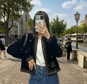 Détails de broderies ethniques dorées et perles sur une veste en velours noir