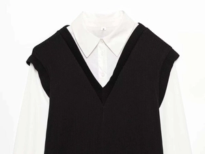 Detail view of stylish black V-neck knit vest layered over a white long sleeve poplin shirt