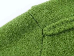 Macro detail of green knit fabric texture showing thick fuzzy material and precision stitching
