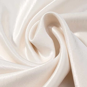 Close-up of champagne satin fabric with elegant silk texture and draped folds for a dress