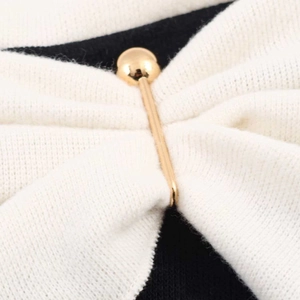 Macro shot of a golden metal pin with a spherical head on white knitted fabric