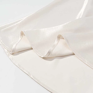 Close-up of champagne satin dress hem with delicate lace trim and pearl luster finish
