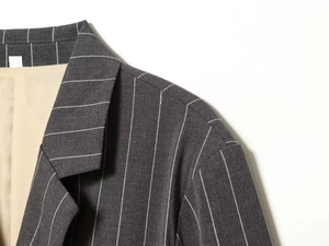 Detail of dark grey pinstriped blazer collar with ivory lining and fine fabric texture
