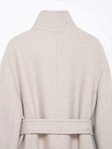 Detail view of the high standing collar and textured wool fabric on a beige pea coat