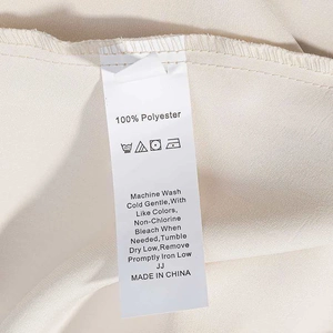 Detail of white satin care label with washing instructions on beige polyester dress